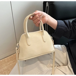 Detail view of cream mini shell bag with lychee texture and metal bottom rivets
