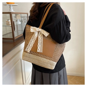 Detail of hand-woven tote bag featuring a cream lace bow and leather handle