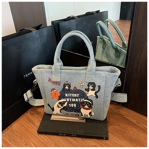 Detail view of light blue denim tote bag with cute cartoon cat and gingerbread man prints