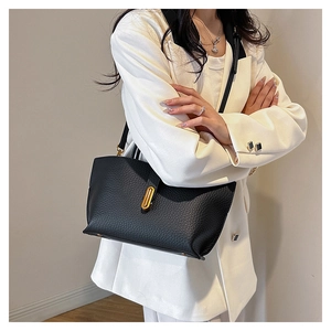 Detail of black pebbled leather tote bag with elegant gold vertical oval clasp for women