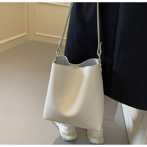 Detail view of white lychee textured tote bag with slender shoulder strap and gold buckle