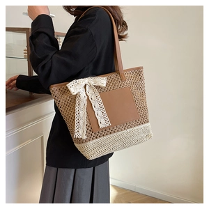 Detail of hand-woven straw tote bag with brown leather straps and white lace bow
