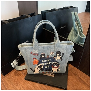 Detail of light blue denim tote with cute cartoon cat prints and adjustable shoulder strap