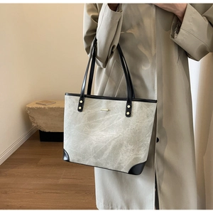 Dettaglio della borsa tote grigia marmorizzata con finiture in pelle nera e dettagli dorati
