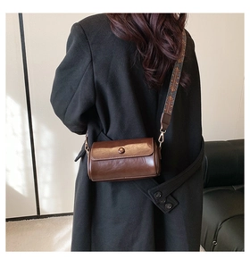 Close-up of vintage dark brown cylinder bag with wide jacquard patterned shoulder strap