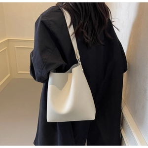 Close-up of minimalist cream-white bucket bag showing premium lychee grain texture