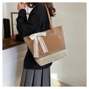 Detail of hand-woven straw tote bag with brown leather patch and white lace bow decoration