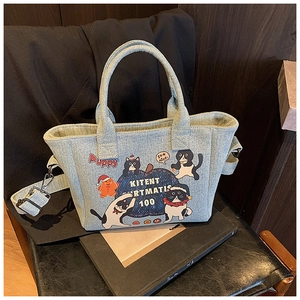 Close-up of light blue denim tote with cute cartoon cat prints and adjustable strap