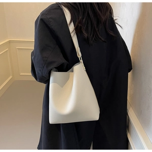 Detailed back view of model wearing a white pebbled leather bucket bag with slender strap