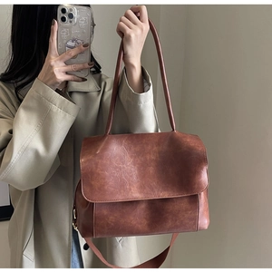 Detailaufnahme der braunen Vintage-Tasche mit breitem Stoffschultergurt und Klappenverschluss