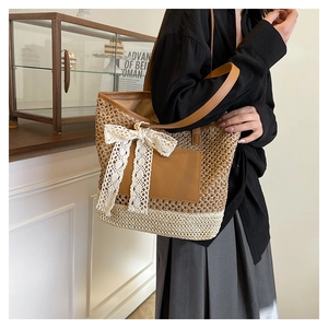 Detail of hand-woven straw tote with leather strap and decorative lace bow