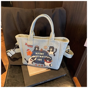 Detail of light blue denim tote bag with cat prints and adjustable shoulder strap