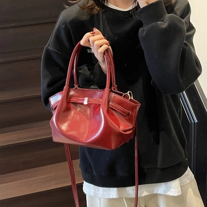 Détail d'un sac cabas en cuir brillant rouge foncé avec plis et boucles argentées