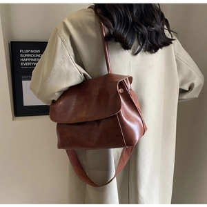 Braune Vintage-Einkaufstasche mit breitem Gurt am Modell zur Inhaltsdarstellung
