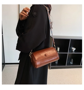 Brown vintage cylinder bag detail with colorful jacquard strap and gold metal hardware