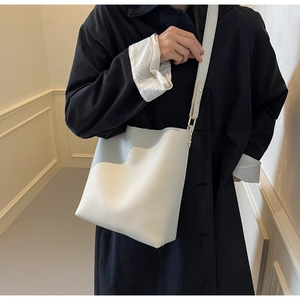 Close-up of a white lychee grain bucket bag with adjustable strap and gold metal hardware