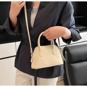 Detail of off-white shell bag showing lychee grain texture and silver zipper hardware
