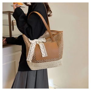 Close-up of a woven tote bag featuring brown leather patches and white lace bow detail