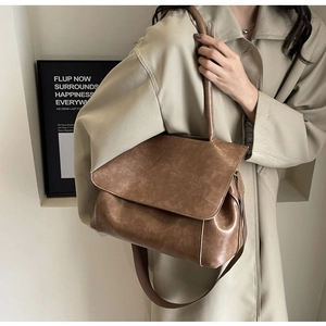 Detailansicht der großen braunen Vintage-Einkaufstasche mit breitem Gurt am Trenchcoat