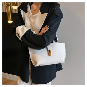 Detail of white lychee leather texture and golden metal twist lock on a tote bag
