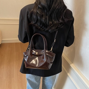 Détail du sac à main marron café en cuir verni avec plis élégants et boucles dorées