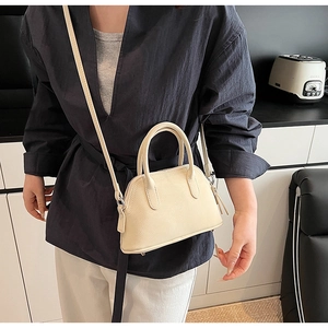 Close-up of cream shell bag featuring lychee grain leather and elegant top handles