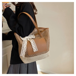 Detail of handwoven straw tote bag with elegant lace bow and bicolor mesh texture