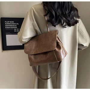 Detail der braunen Vintage-Leder-Einkaufstasche mit breitem Gurt und beigem Trenchcoat