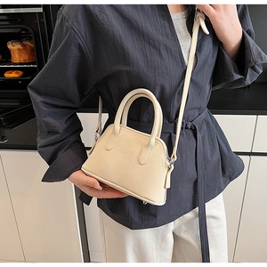 Close-up of a cream shell bag with lychee texture leather and adjustable shoulder strap