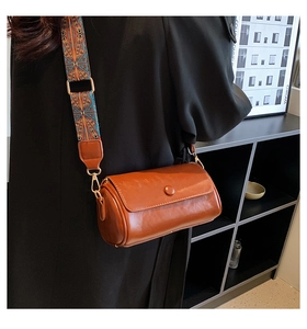 Detail of a brown PU leather barrel bag with vintage ethnic patterned wide shoulder strap