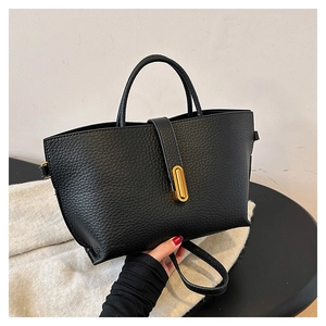 Detailed shot of black lychee grain leather tote bag with gold oval metal lock
