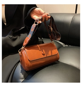 Detail of brown cylinder bag featuring a vintage ethnic pattern wide shoulder strap