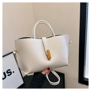 Detail of cream white pebbled leather tote bag featuring a gold oval twist lock closure
