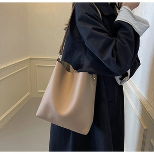 Detail of beige tote bag showing high-quality lychee grain leather texture and handle