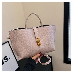 Detailed macro view of the pink lychee leather texture and golden metal buckle on tote bag