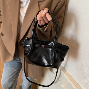 Détail du cabas en cuir verni noir brillant avec poignées rondes et bandoulière