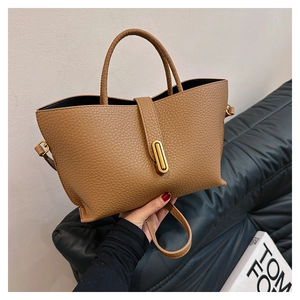 Detail of tan pebble leather tote bag showing golden oval lock and texture