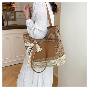 Detail of hand-woven straw tote bag with brown leather patch and white lace bow decoration
