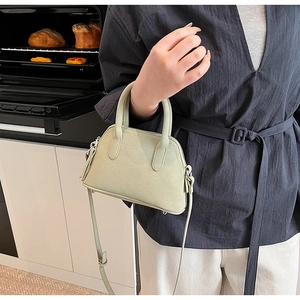 Detail of mint green mini shell crossbody bag with litchi grain texture and silver hardware