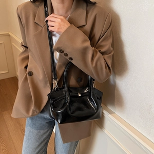 Détail d'un sac cabas noir brillant avec finition cuir lisse et poignée élégante