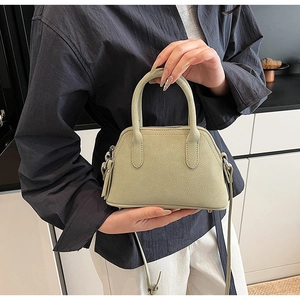 Close-up of light green mini crossbody bag with litchi texture and silver zipper
