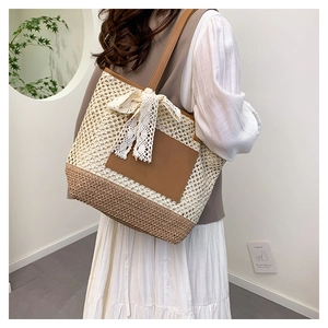 Close-up of woven straw tote bag with brown leather patch and white lace bow detail