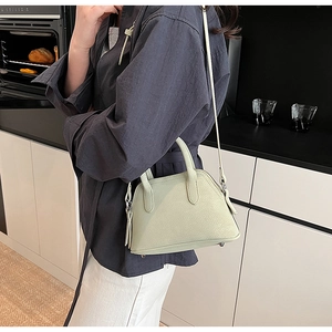 Detail of sage green faux leather crossbody bag with top handles and adjustable strap
