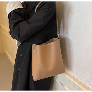 Close-up of brown pebbled leather bucket bag with metal buckle and rivet details