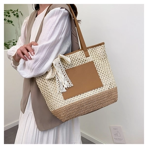 Détail du sac cabas en paille avec nœud en dentelle blanche et poche en cuir marron