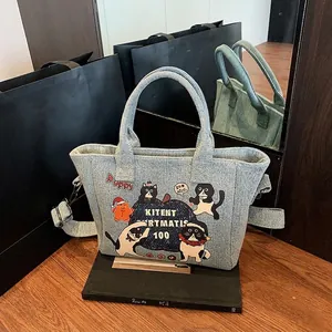 Light blue denim tote bag with cute cartoon cat prints and adjustable shoulder straps