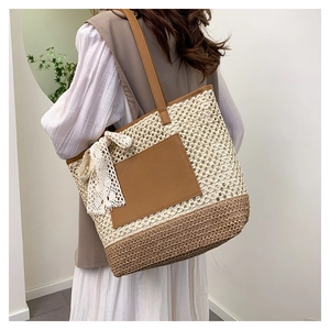 Détail du sac cabas en paille tissée avec nœud en dentelle blanche et anse en cuir brun