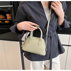 Sage green pebbled leather mini handbag shown on a model to display the actual scale