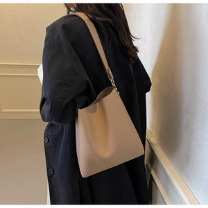 Close-up of beige lychee textured leather bucket bag with detailed metallic strap buckle