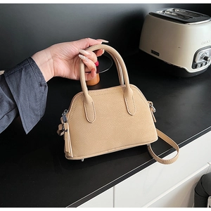 Macro detail of tan lychee grain leather mini handbag with silver zipper and thick handle